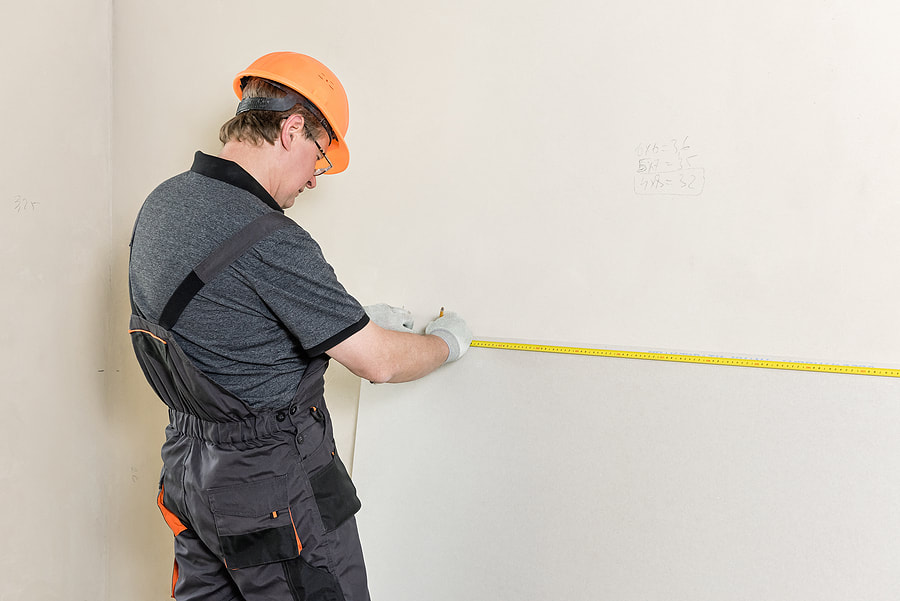 worker measuring the walls